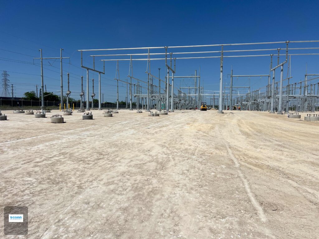 Electrical substation under construction with metal structures and equipment. Clear blue sky and unfinished ground area indicate ongoing development.
